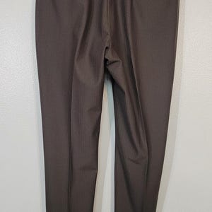 May include: A pair of dark brown dress trousers with a subtle pinstripe pattern. The trousers have a classic fit and a straight leg.