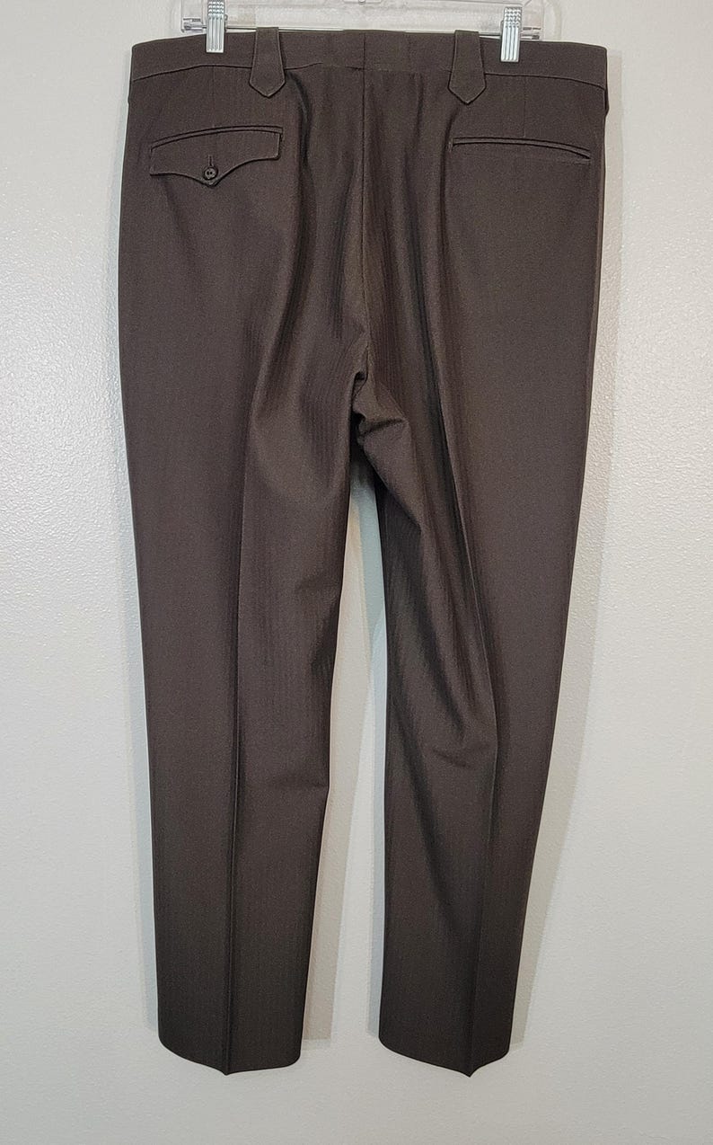 May include: A pair of dark brown dress trousers with a subtle pinstripe pattern. The trousers have a classic fit and a straight leg.