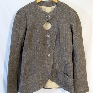 May include: A brown tweed blazer with a unique cut-out detail at the neckline and silver button closures.