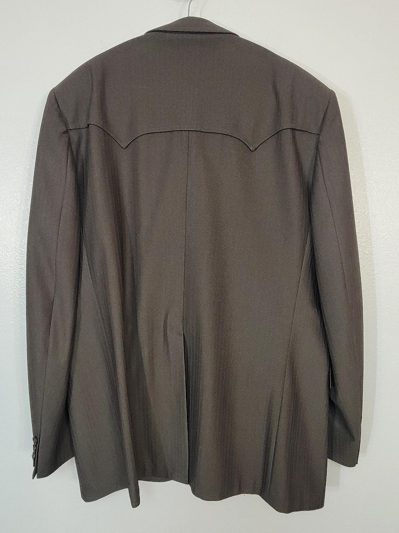 May include: A dark brown blazer with a subtle pinstripe pattern. The blazer has a single-breasted closure and a notched lapel.