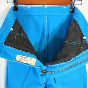 Puede incluir: Un par de pantalones vaqueros azules de mezclilla con cierre de cremallera y una etiqueta Wrangler. Los pantalones est&aacute;n dados vuelta para mostrar el forro negro.