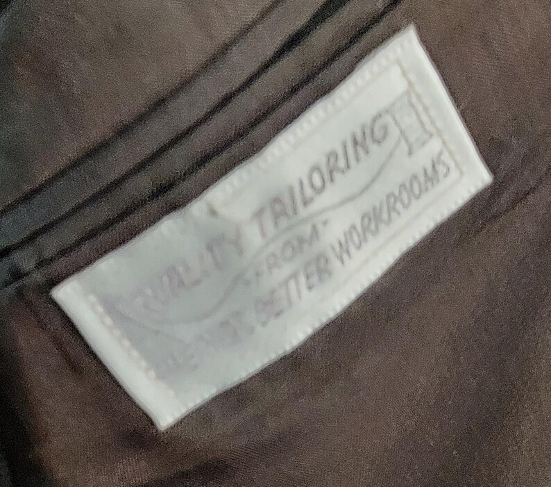 May include: A white label sewn into a brown fabric garment with the text "Quality Tailoring From Our Better Workrooms".