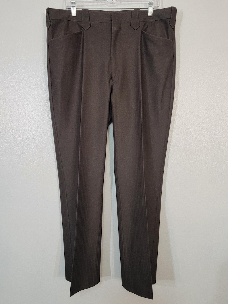 May include: A pair of brown pinstripe trousers with a straight leg fit. The trousers have a zip fly and button fastening.