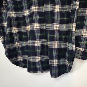 Pu&ograve; includere: Una camicia a maniche lunghe con bottoni caratterizzata da un motivo a quadri in blu navy scuro, verde bosco e bianco crema con sottili linee gialle. Il capo presenta un colletto classico, un'abbottonatura frontale e polsini con bottoni.