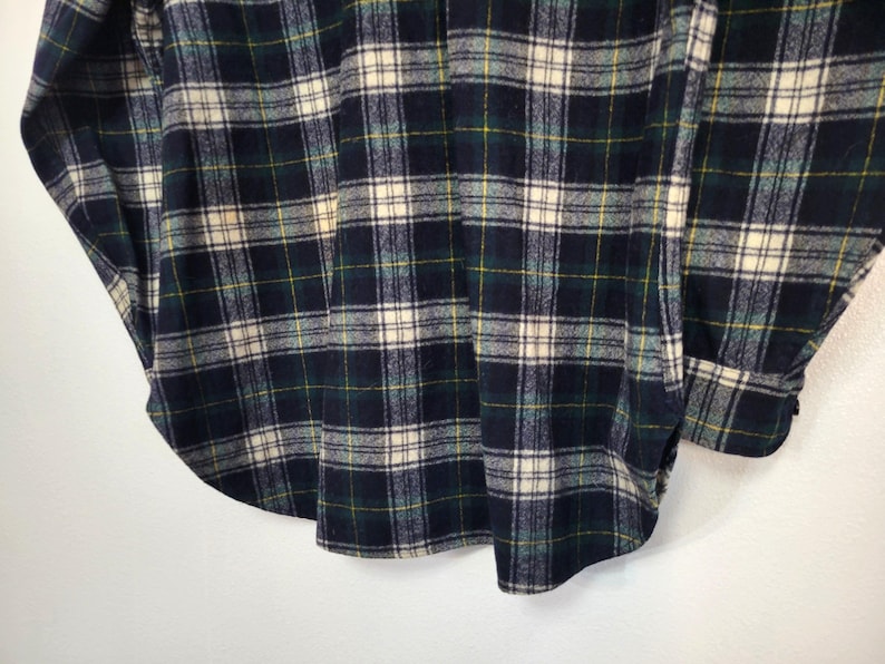 Pu&ograve; includere: Una camicia a maniche lunghe con bottoni caratterizzata da un motivo a quadri in blu navy scuro, verde bosco e bianco crema con sottili linee gialle. Il capo presenta un colletto classico, un'abbottonatura frontale e polsini con bottoni.