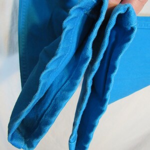 Puede incluir: Primer plano del interior de dos mangas de tela azul brillante. Las mangas est&aacute;n dobladas por la mitad y las costuras son visibles.
