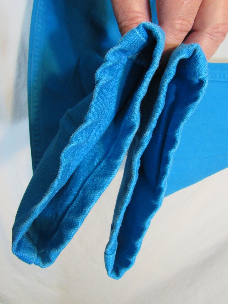 Puede incluir: Primer plano del interior de dos mangas de tela azul brillante. Las mangas est&aacute;n dobladas por la mitad y las costuras son visibles.