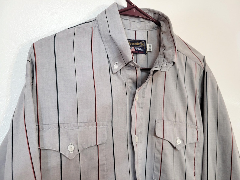 May include: A gray button-down shirt with vertical stripes in black, red, and green. The shirt has two chest pockets and a button-down collar. The brand name "Panhandle Slim" is visible on a tag.