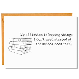May include: A white card with black text that reads "My addiction to buying things I don't need started at the school book fair." A black and white illustration of a stack of books is above the text.
