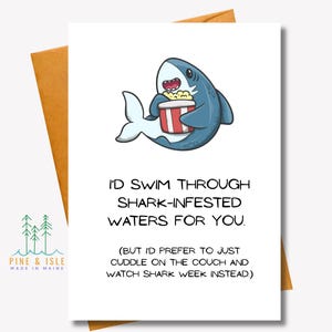 May include: A white greeting card with a cartoon shark holding popcorn. The card reads, "I'D SWIM THROUGH SHARK-INFESTED WATERS FOR YOU. (BUT I'D PREFER TO JUST CUDDLE ON THE COUCH AND WATCH SHARK WEEK INSTEAD.)" The card is in a brown envelope.