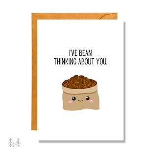 May include: A white card with brown text that reads "I've bean thinking about you." A cartoon illustration of a brown paper bag with a smiling face filled with brown coffee beans.