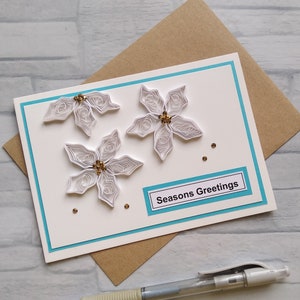 Tarjeta de felicitación navideña con flor de Pascua blanca y arte de filigrana de papel en 3D