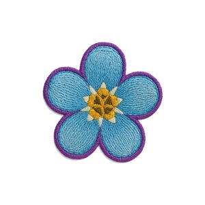 Peut inclure: Un écusson en forme de fleur à cinq pétales avec des pétales brodés bleu clair et une bordure violet foncé. Le centre de la fleur est composé d'un amas texturé jaune et doré entouré de petits accents blancs pointus.