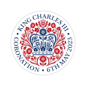 Peut inclure: Un cercle blanc avec un motif bleu et rouge. Le motif représente une couronne avec des accents floraux et le texte "KING CHARLES III CORONATION 6TH MAY 2023".