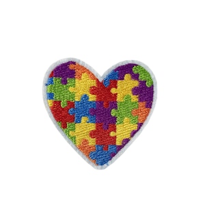 May include: Heart-shaped embroidered patch with a jigsaw puzzle design. The puzzle pieces are in red, orange, yellow, green, blue, and purple, with a white border. This patch is suitable for various applications and can be sewn or ironed on.