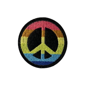May include: A rainbow peace sign embroidered patch. The patch is circular and features a black peace symbol with a rainbow of colours around the outside.