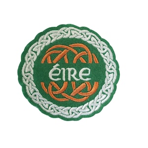Könnte beinhalten: Ein grüner Filzkreis mit einem weißen keltischen Knotenrand. Die Mitte zeigt ein orangefarbenes keltisches Knotendesign und das Wort "éire" in weißen Buchstaben.