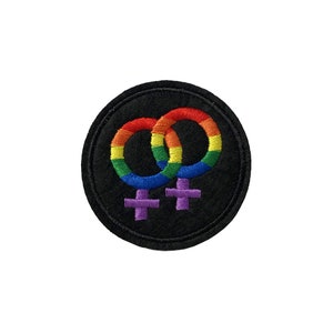 May include: A rainbow-coloured female symbol with two interlocking circles, embroidered on a black felt patch.