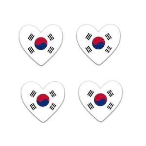 May include: Four white heart-shaped stickers featuring the South Korean flag. Each sticker has a white background with the Taegeuk symbol in the center, surrounded by four black trigrams. The Taegeuk symbol is a circle divided into red and blue sections.