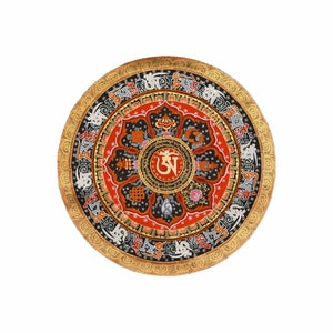 May include: A circular mandala with a gold border and intricate black, red, and white designs. The centre of the mandala features a gold "Om" symbol surrounded by a lotus flower.