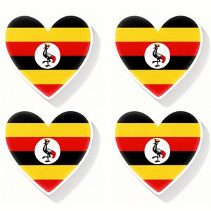 May include: Four heart-shaped stickers displaying the Ugandan flag. Each sticker has horizontal stripes of black, yellow, and red, with a white circle and a crested crane emblem in the centre. The stickers have a white border.