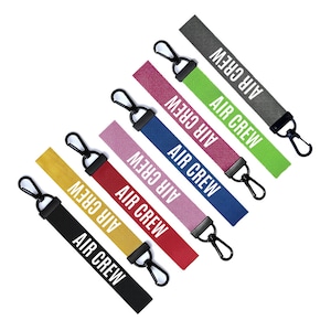 May include: Seven colourful keychains with black metal clasps. Each keychain has a white fabric strap with the text "AIR CREW" printed on it.