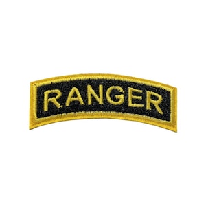 May include: A black and gold embroidered patch with the word "RANGER" in yellow capital letters. The patch has a curved shape and a gold border. The text is centered on the patch.