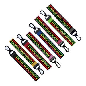 Puede incluir: Siete llaveros coloridos con anillos de metal negro. Cada llavero tiene un fondo a rayas negro, rojo, verde y amarillo con el texto "Defiende tus derechos. Un pueblo, un amor, un mundo. El poder al pueblo." repetido en cada llavero.