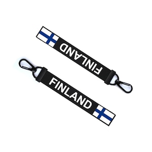 May include: Two black keychains with a white "FINLAND" text and the Finnish flag. Each keychain has a black metal hook.