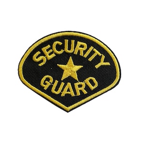 May include: Embroidered patch in black and gold, featuring the text "SECURITY GUARD" and a gold star. The patch has a black background with gold lettering and a gold border.