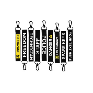 Puede incluir: Conjunto de ocho llaveros negros con texto blanco y detalles amarillos. Los llaveros presentan varias frases, entre ellas "Biohazard", "Freedom", "Technician", "Staff", "Police", "Danger", "Laundry Key", "Spare Keys" y "Your Text Here".