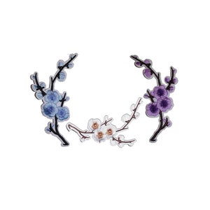 May include: Three embroidered iron-on patches featuring floral designs. The patches are in shades of blue, purple, and white.