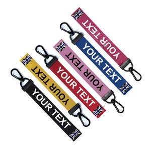 May include: Five colourful keychains with black metal rings and a small flag design. Each keychain has the text "YOUR TEXT" printed on it.
