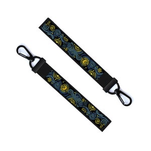 May include: Two black keychains with a blue and yellow starry night design. The keychains have a metal clasp.