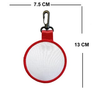 May include: A round, white keychain with a red border, measuring 7.5 cm wide and 13 cm long. It features a red fabric loop and a black metal clip for attachment. The keychain is designed with a mesh-like white center.
