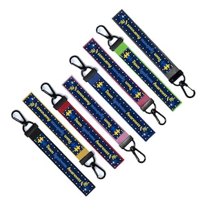 May include: Eight blue and yellow keychains with the text "Down Syndrome Awareness" and a puzzle piece design. Each keychain has a different colored strap.
