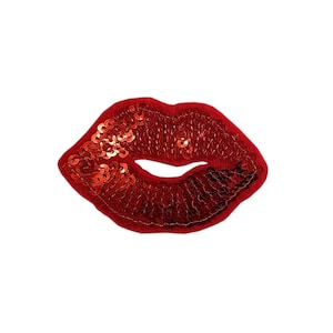 Puede incluir: Un parche de labios rojos con lentejuelas. El parche tiene la forma de un par de labios, con la boca ligeramente abierta. Las lentejuelas son de color rojo brillante y el parche tiene un reverso de fieltro. El parche de labios es un accesorio divertido y moderno.