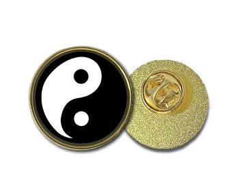 May include: A gold-colored pin with a black and white yin yang symbol on the front. The back of the pin has a standard pin back.