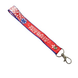 Könnte beinhalten: Rotes und blaues Lanyard mit dem Text "Medical Alert Pacemaker" und einem Stern-des-Lebens-Symbol. Das Lanyard hat einen silbernen Metallclip.