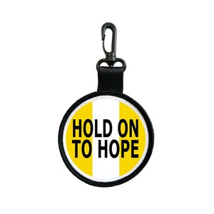 May include: A round, yellow and white patch with the text "HOLD ON TO HOPE" in black. The patch has a black border and is attached to a black strap and a black metal clip.