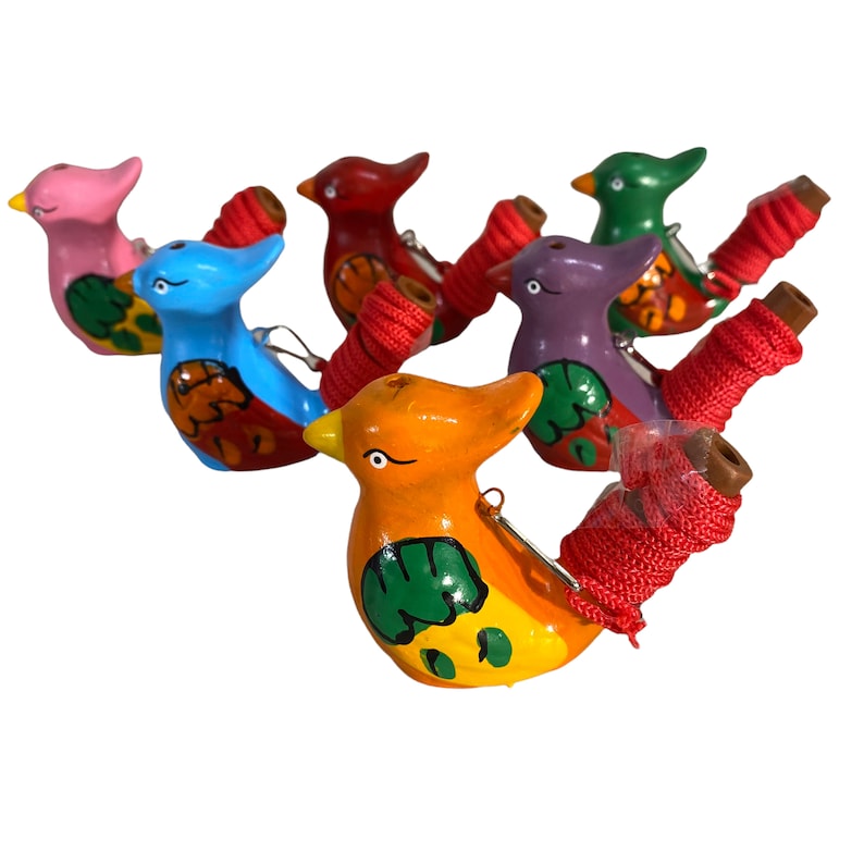 Puede incluir: Un conjunto de seis silbatos de colores con forma de p&aacute;jaro con una cuerda roja atada a cada uno. Los silbatos est&aacute;n pintados con varios patrones y colores, incluyendo rosa, azul, rojo, verde, morado y naranja.