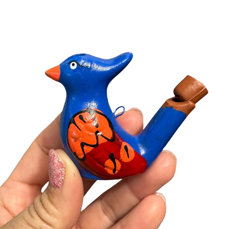 Puede incluir: Un silbato de p&aacute;jaro azul y naranja con un agujero de silbato marr&oacute;n. El p&aacute;jaro tiene un dise&ntilde;o rojo y naranja en su cuerpo.