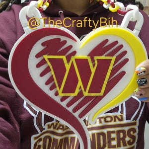 May include: A heart-shaped pendant with a white background, a burgundy border, and a yellow accent. The letter "W" is in the center. Matching earrings and a necklace are also visible. The text "@TheCraftyBih" is in the image.