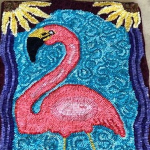 May include: A pink flamingo stands in a blue and green water scene with yellow palm trees. The rug is made of looped yarn and is a colorful and whimsical design.