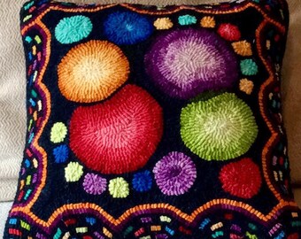Peut inclure: Un coussin noir avec un motif abstrait coloré. Le coussin présente une variété de formes rondes brillantes dans des tons de rouge, orange, jaune, vert, bleu et violet. Les formes sont disposées de manière aléatoire sur le fond noir.