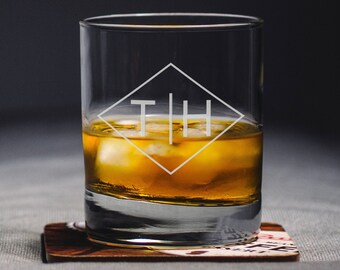 May include: A clear glass with a diamond-shaped design etched on the front. The glass is filled with amber liquid and ice cubes. The diamond design contains the letters "TIH" in a sans-serif font.