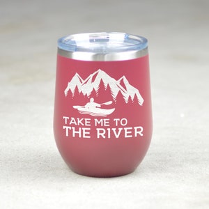 Puede incluir: Un vaso de acero inoxidable color burdeos con un dise&ntilde;o blanco de monta&ntilde;as, &aacute;rboles y una persona en kayak. El texto "Take me to the river" est&aacute; impreso debajo del dise&ntilde;o.
