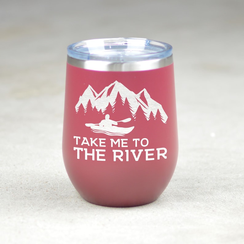 Puede incluir: Un vaso de acero inoxidable color burdeos con un dise&ntilde;o blanco de monta&ntilde;as, &aacute;rboles y una persona en kayak. El texto "Take me to the river" est&aacute; impreso debajo del dise&ntilde;o.