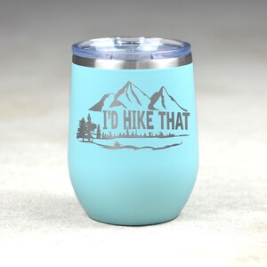 May include: A light blue stainless steel tumbler with a silver lid and a mountain silhouette with the text "I'd Hike That".