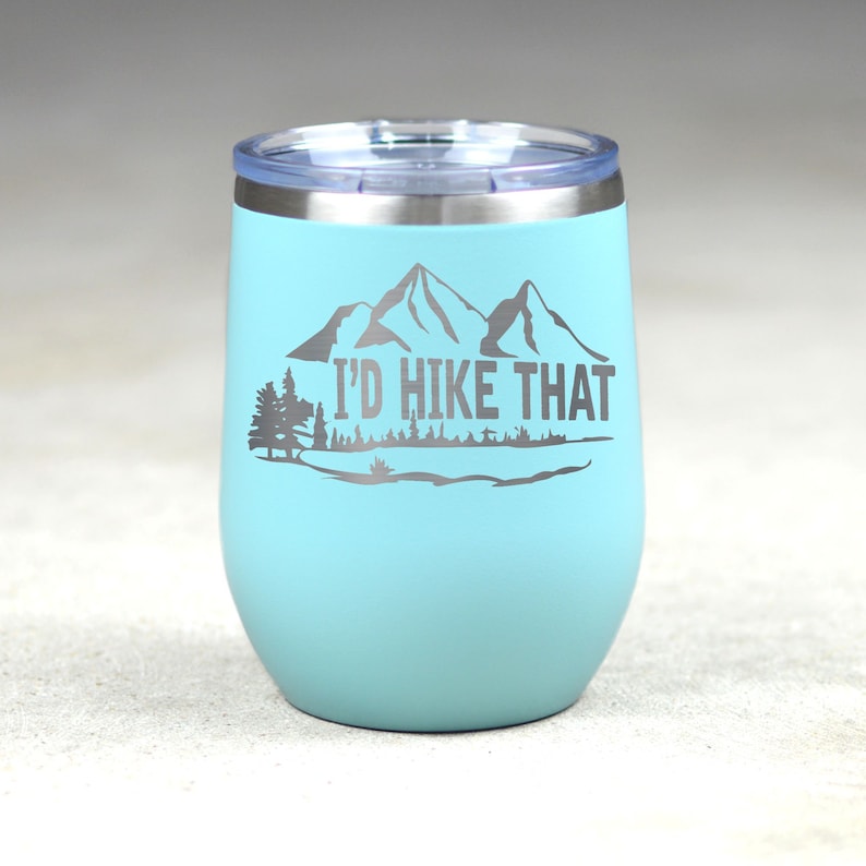 May include: A light blue stainless steel tumbler with a silver lid and a mountain silhouette with the text "I'd Hike That".